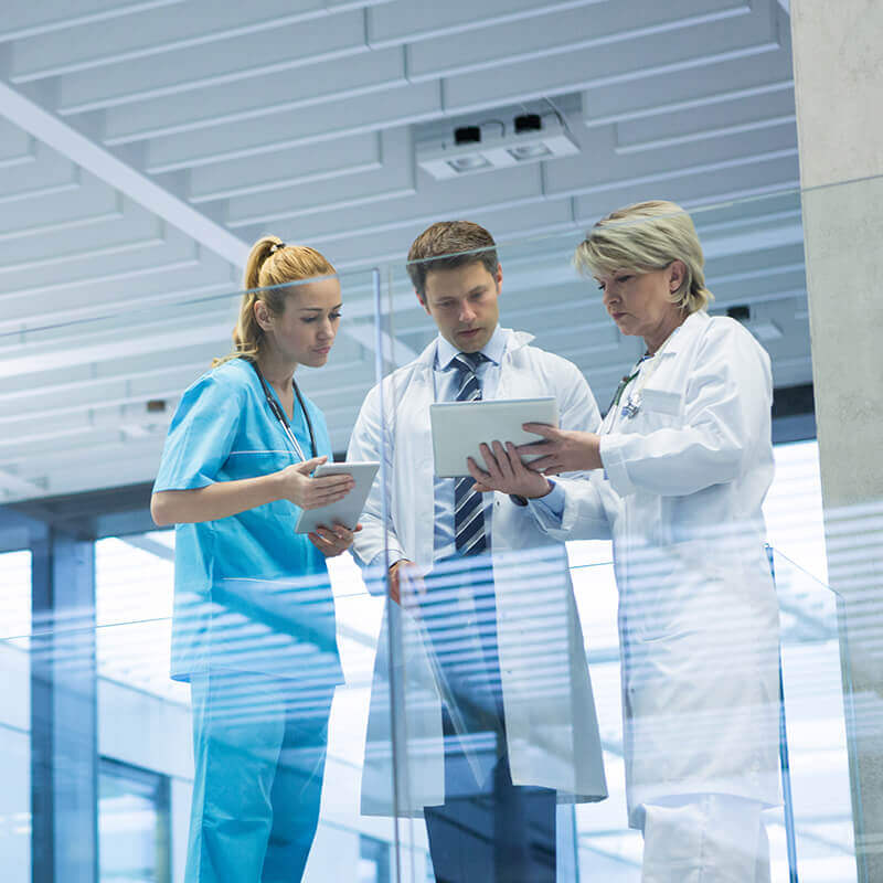 zwei Ärzte und eine Krankenschwester schauen auf Tablet